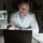 Male doctor in white coat gesturing on a video call late at night